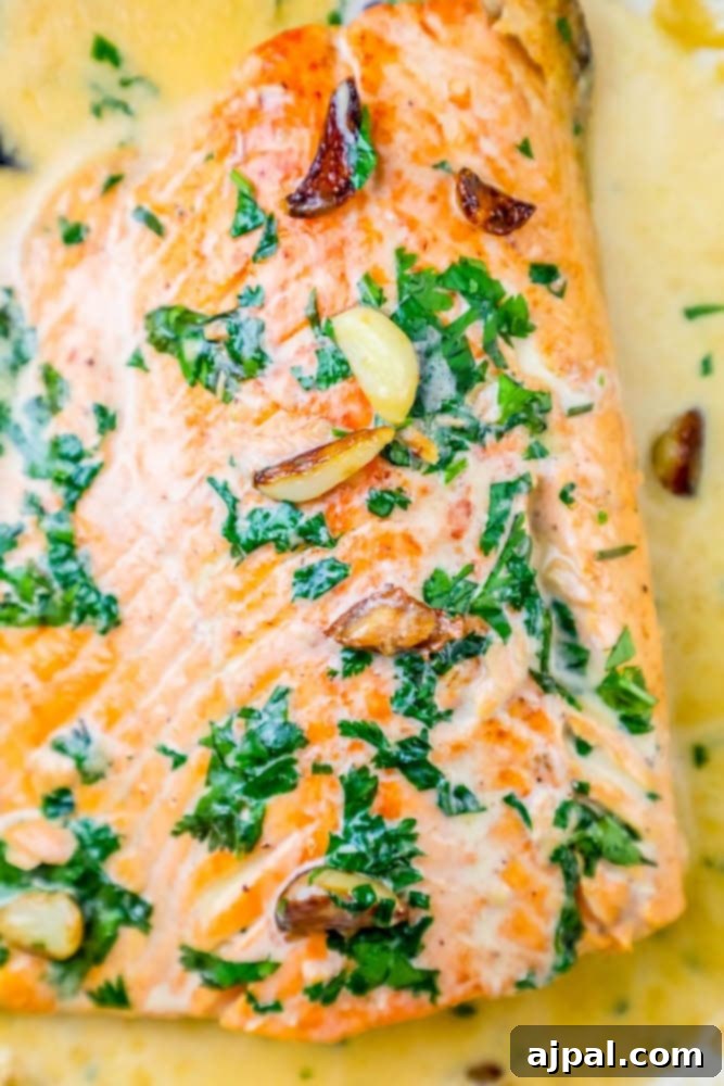 whiskey cream sauce salmon topped with chopped parsley and garlic cloves on top 