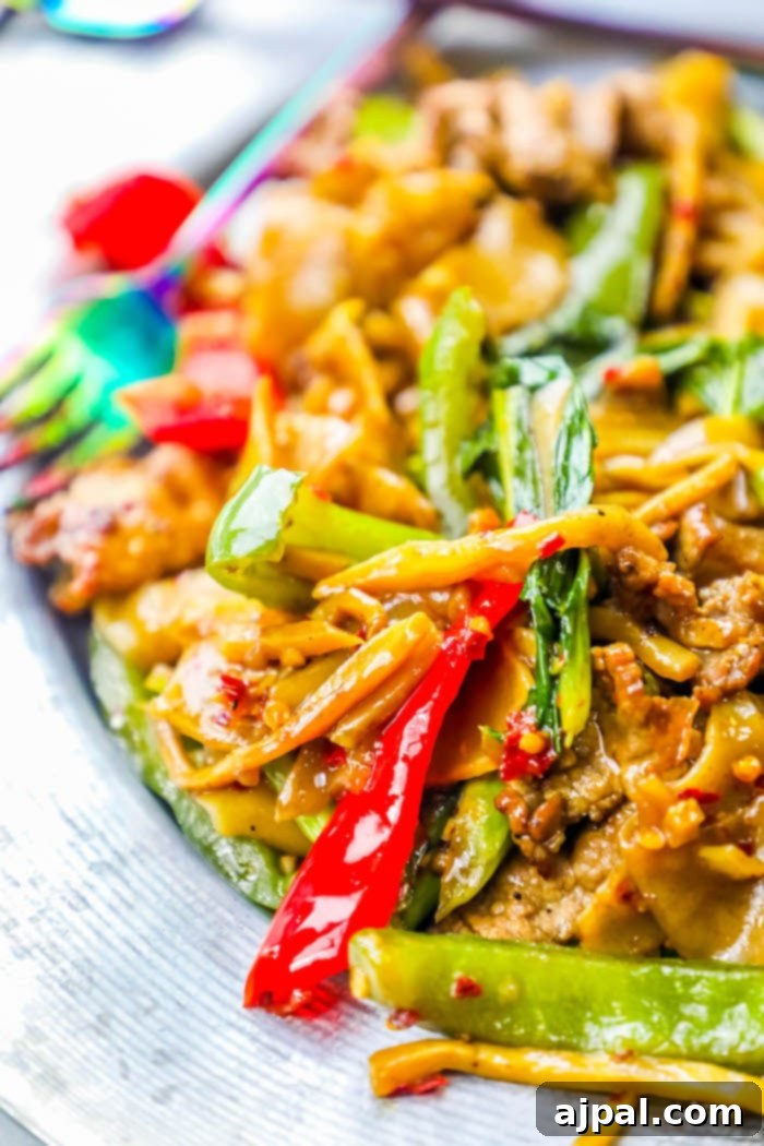 Effortless One Pot Beef Drunken Noodles 3 A close-up shot of perfectly cooked Beef Drunken Noodles served on a sleek metal plate, adorned with fresh basil and chili.