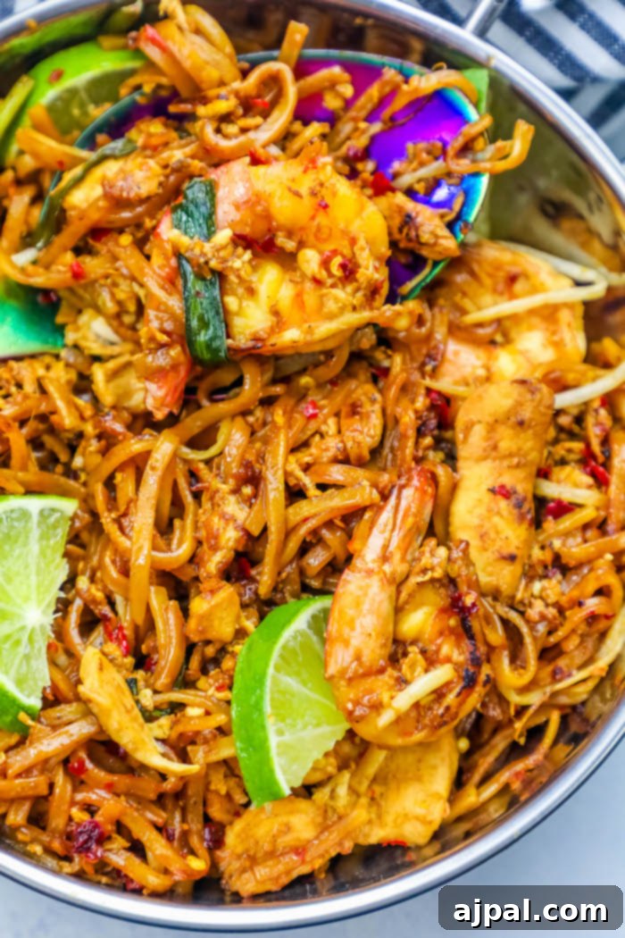 Effortless Chicken and Shrimp Pad Thai 3 Close-up of freshly cooked Thai fried noodles with shrimp and chicken, brightened with lime wedges, ready for an easy dinner.