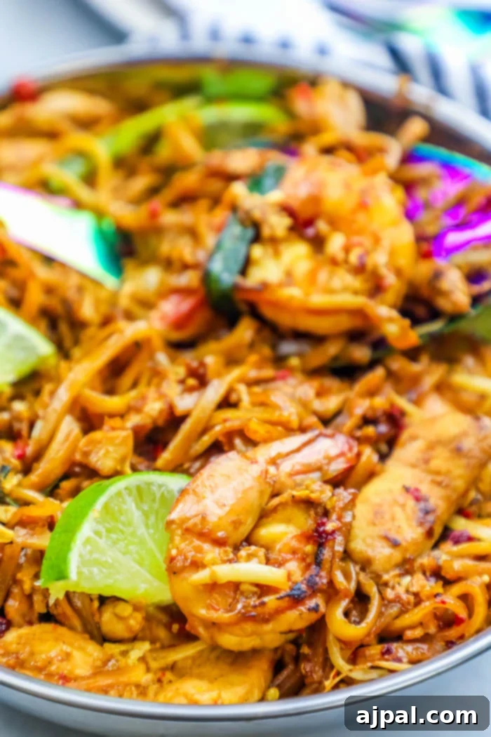 Effortless Chicken and Shrimp Pad Thai Noodles 4 A wok filled with sizzling chicken and shrimp pad thai, featuring a rich, savory sauce, ready for the final touches of fresh ingredients.