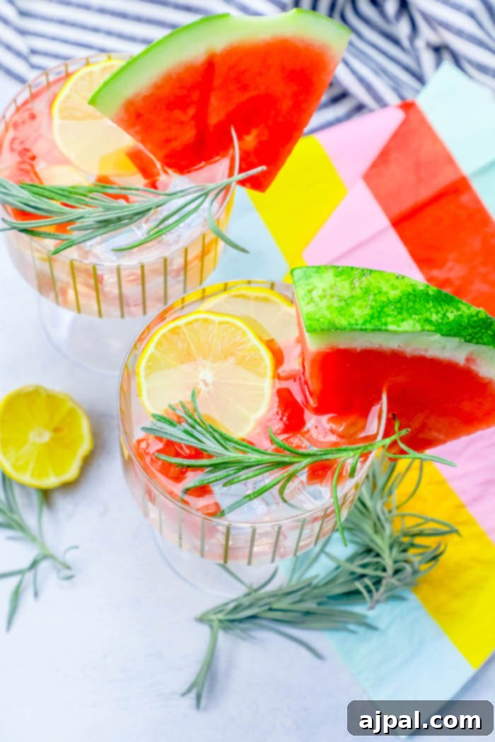 Spiked Watermelon Rosemary Lemonade 3 A close-up of a vibrant watermelon vodka drink, garnished with fresh lemon slices and a sprig of rosemary.