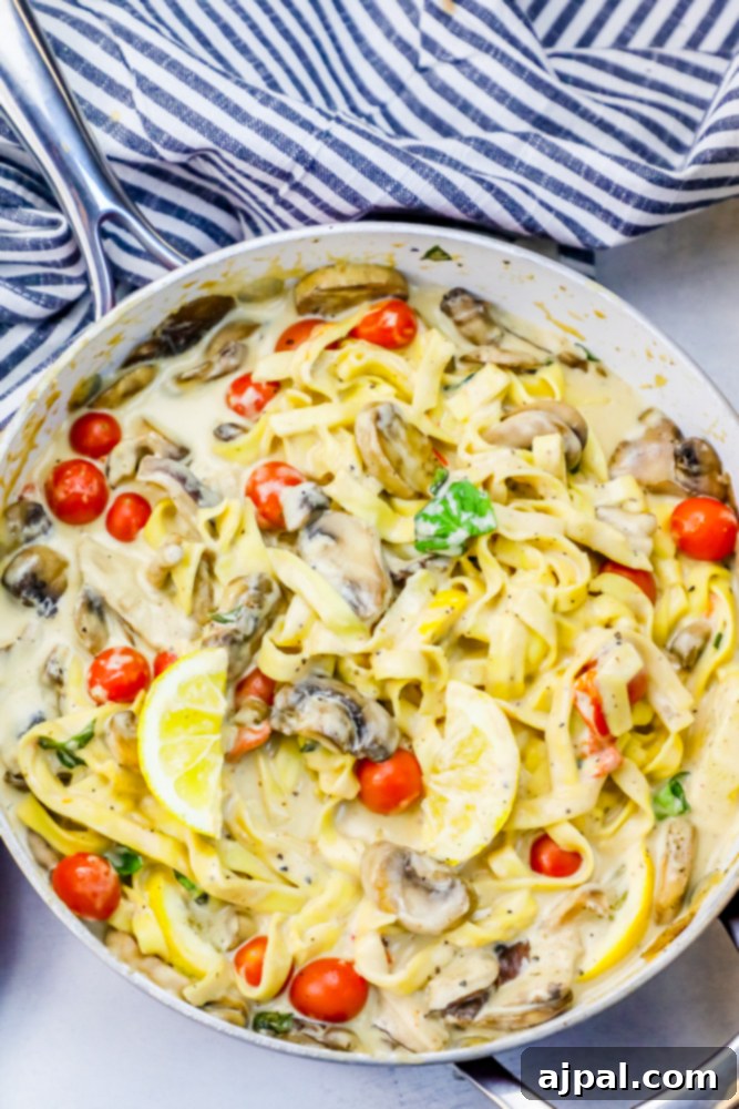 Silky One-Pot Tuscan Mushroom Linguine 3 Close-up of creamy mushroom pasta with tomatoes and fresh herbs in a pan.