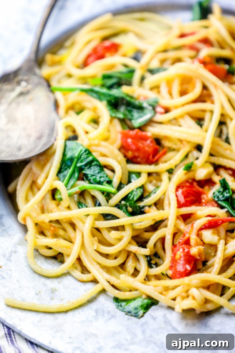 Garlic Butter Spinach Parmesan Spaghetti 3 A close-up of the One-Pot Spinach Parmesan Garlic Butter Spaghetti, highlighting the glistening pasta, vibrant spinach, and plump cherry tomatoes.