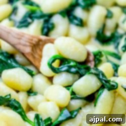 Cook store-bought gnocchi with parmesan and spinach, using a wooden spoon.