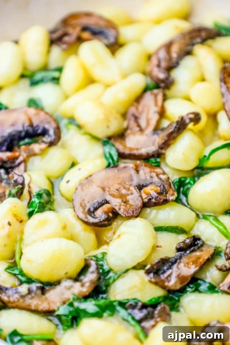 Gnocchi with creamy mushroom and spinach sauce in a skillet.