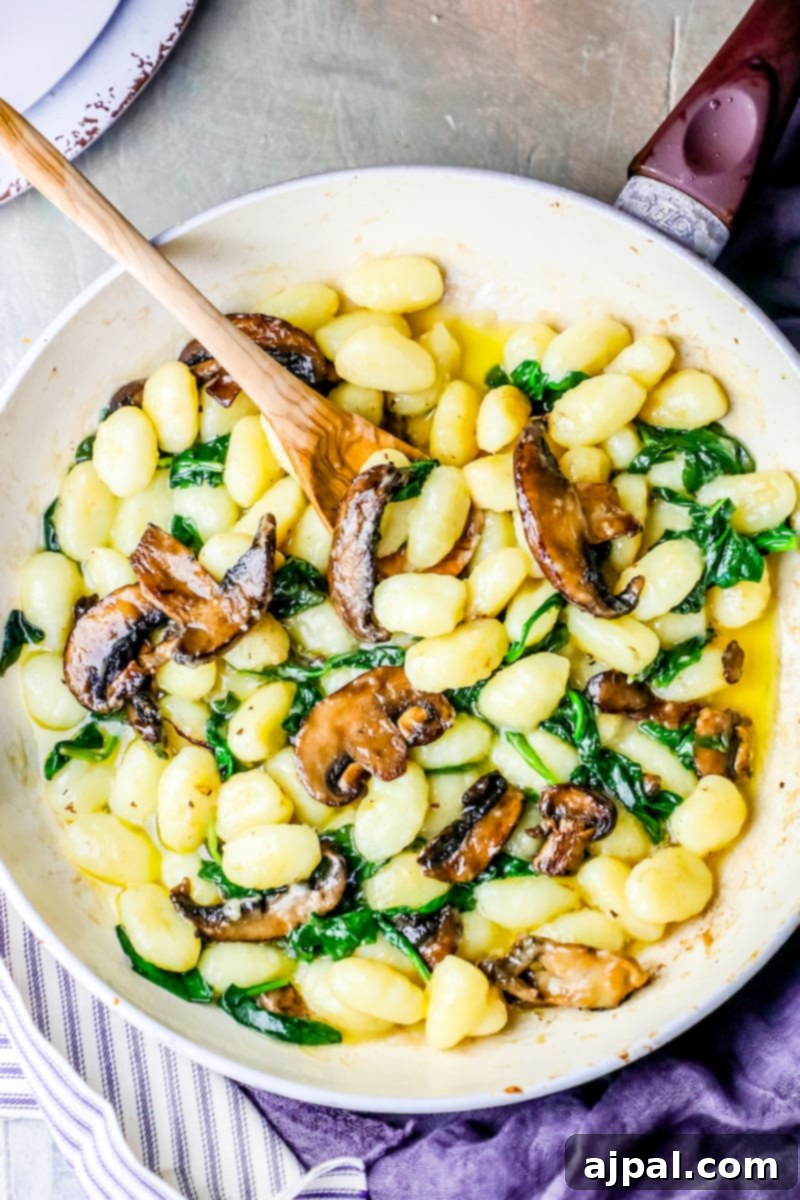 A creamy dish of mushroom and spinach with a wooden spoon.