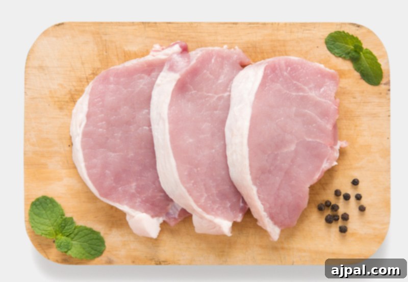 Several boneless pork loin chops arranged on a wooden cutting board, showcasing their lean appearance.