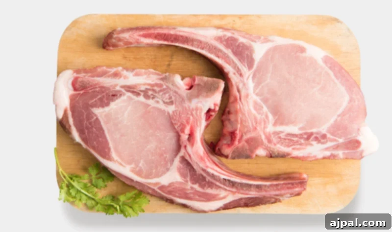 Two bone-in pork rib chops resting on a rustic wooden cutting board.