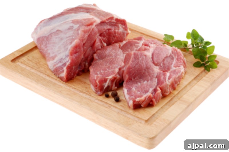 A thick, dark shoulder pork chop with visible marbling and a bone, placed on a cutting board.