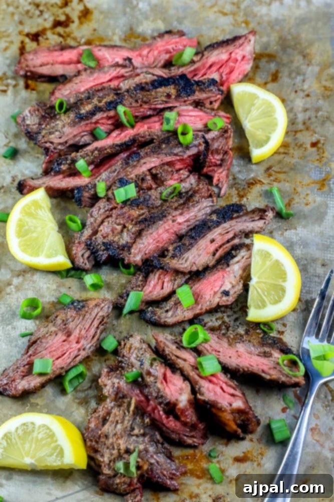 Mastering Grilled Flank Steak 2 Grilled flank steak garnished with lemon slices and chives on a serving tray, showcasing its perfectly charred exterior.