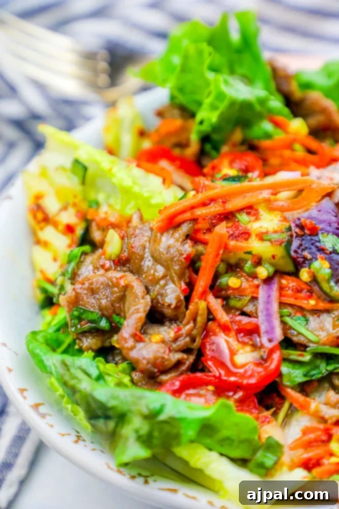 Fiery Thai Beef Salad 4 A vibrant keto-friendly Thai beef salad, beautifully plated with crisp lettuce, carrots, and a spicy dressing, emphasizing fresh ingredients.