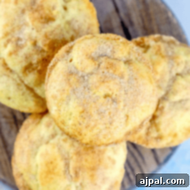 A close-up of Sour cream snickerdoodle mini muffins dusted with cinnamon-sugar on a wooden surface.