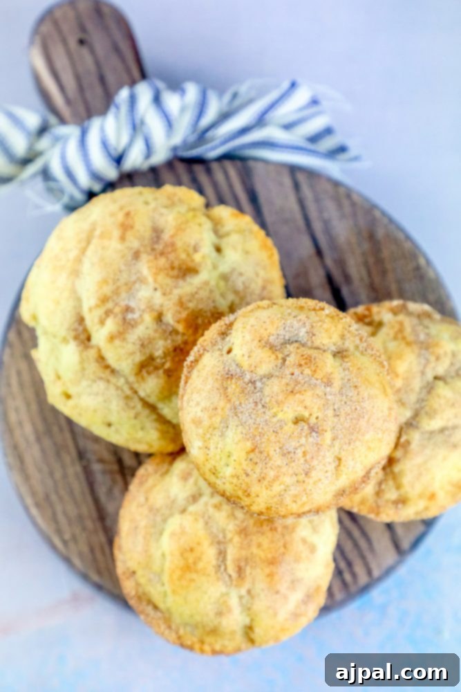 A rustic cutting board laden with a generous pile of snickerdoodle muffins, beautifully browned and coated in glistening cinnamon sugar, ready for serving.