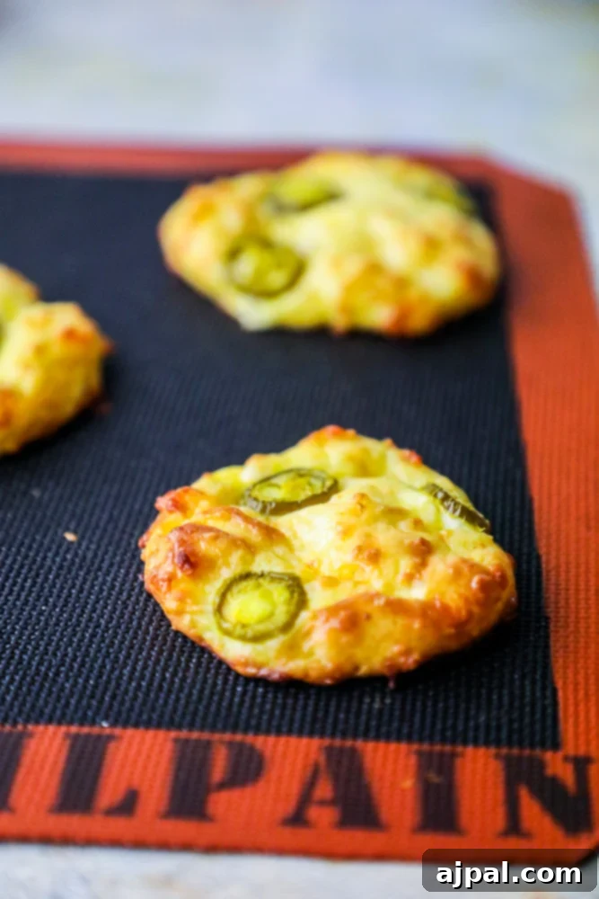 4 Ingredient Keto Jalapeno Cheese Loaf 5 Four delicious cheesy jalapeno bread rolls resting on a perforated baking mat, ready to be served.
