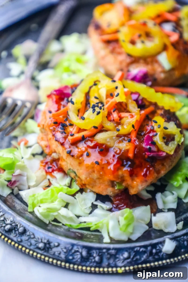 Sweet Chili Glazed Asian Salmon Burgers 3 Two perfectly cooked Asian Grilled Salmon Burgers with fresh vegetables, showcasing their vibrant appeal and healthy ingredients.