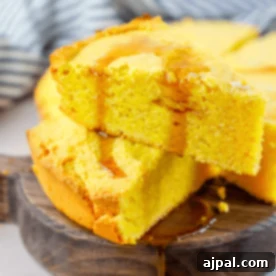 A slice of cornbread on a wooden plate, made with the best cornbread recipe ever.
