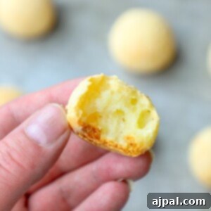 A person's hand holding a piece of Brazilian Cheese Bread Rolls.