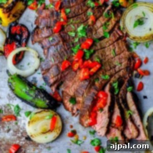 Ultimate Carne Asada 10 The Best Grilled Carne Asada Recipe Ever featuring a steak cooked with peppers and onions on a baking sheet.