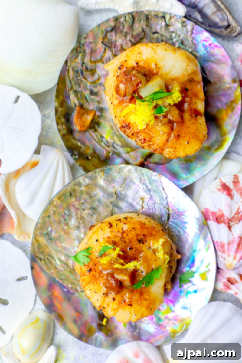 Two perfectly pan-seared lemon garlic scallops on a seashell plate, ready to be enjoyed.