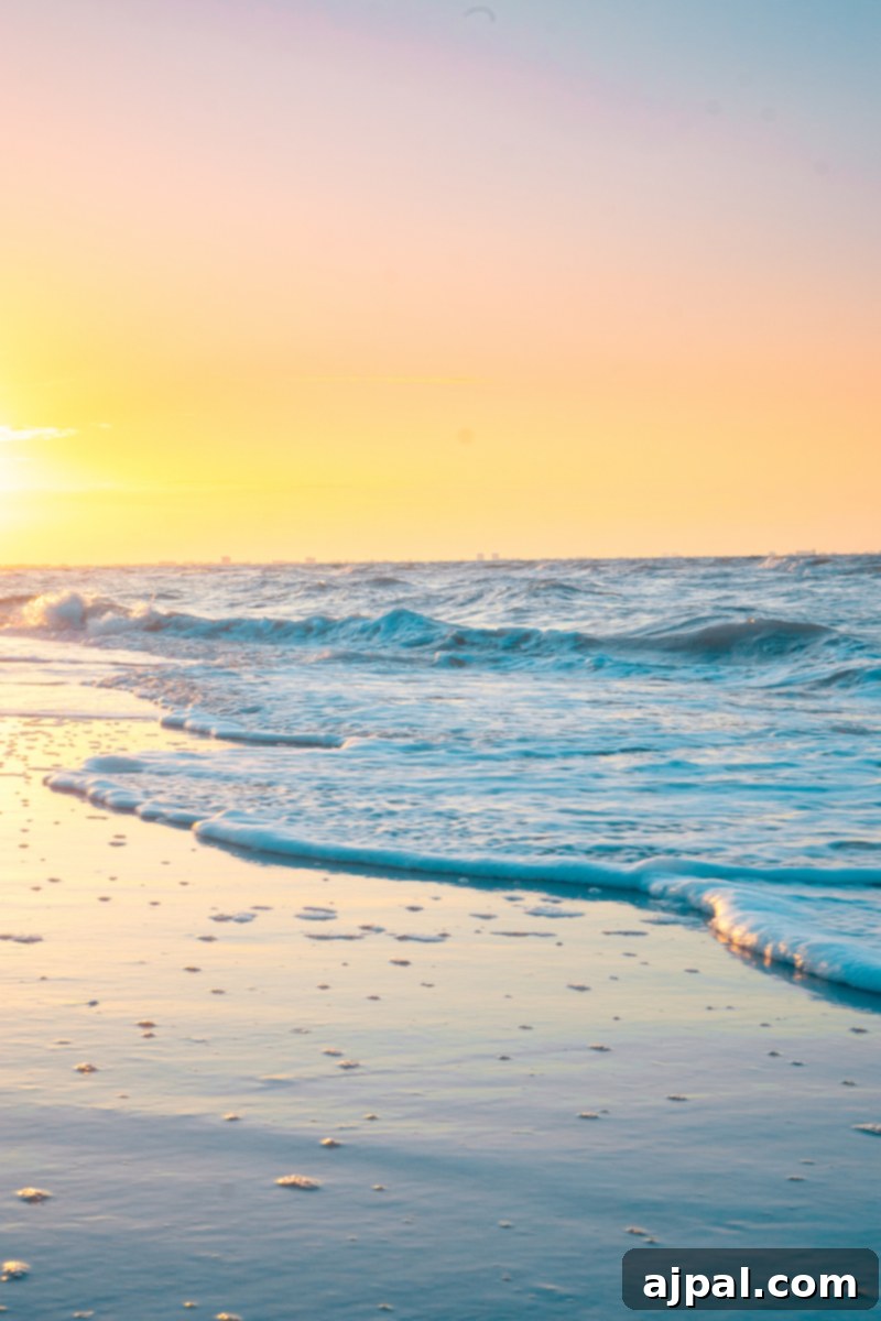 A serene beach at sunrise on Sanibel Island, Florida, with soft waves lapping the shore.