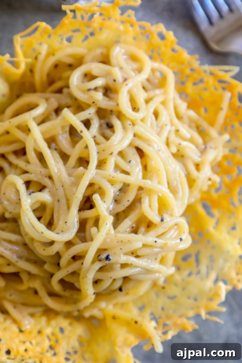 Creamy parmesan and pepper pasta served in a decorative parmesan bowl on a rustic table, highlighting its rich texture and appealing presentation.