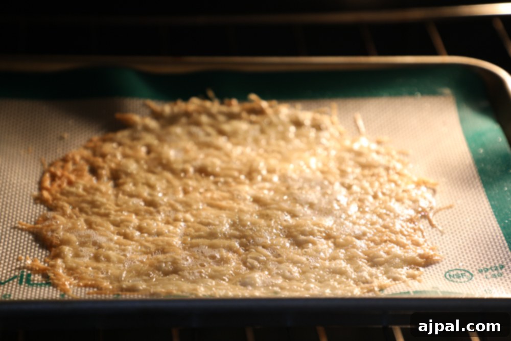 Melted and bubbly Parmesan cheese on a baking sheet, golden brown and perfectly cooked for shaping into an edible bowl.