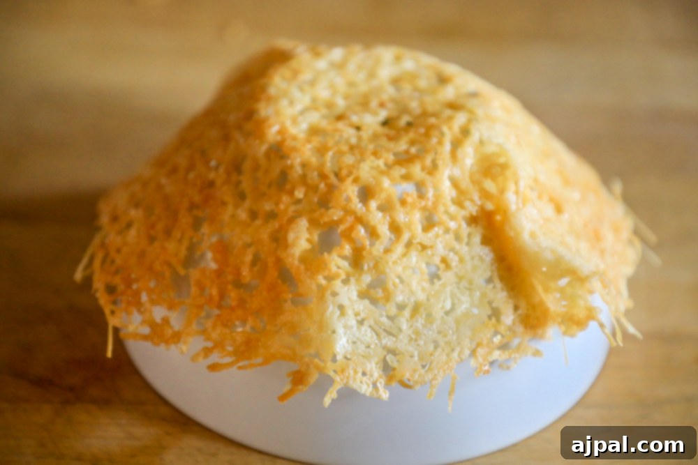 A warm, pliable Parmesan crisp being shaped over an inverted bowl to form an edible cheese bowl, adding a creative touch to a Cacio e Pepe recipe.