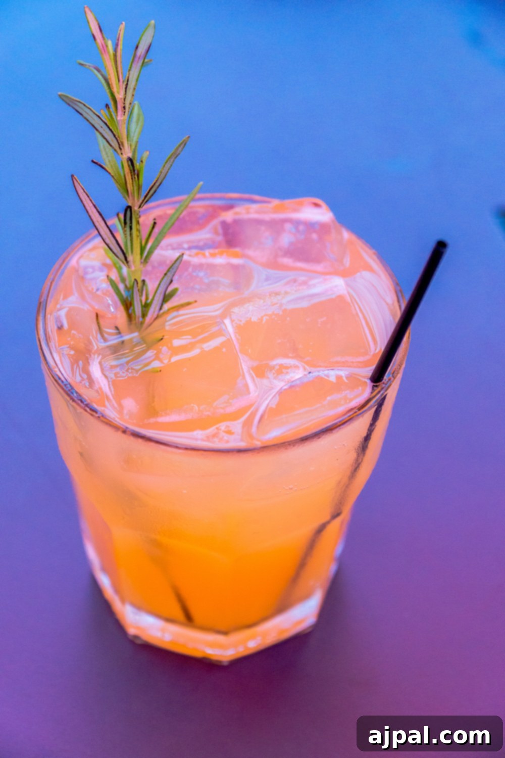 A refreshing cocktail garnished with a rosemary sprig, perfect for Kansas City food enthusiasts.