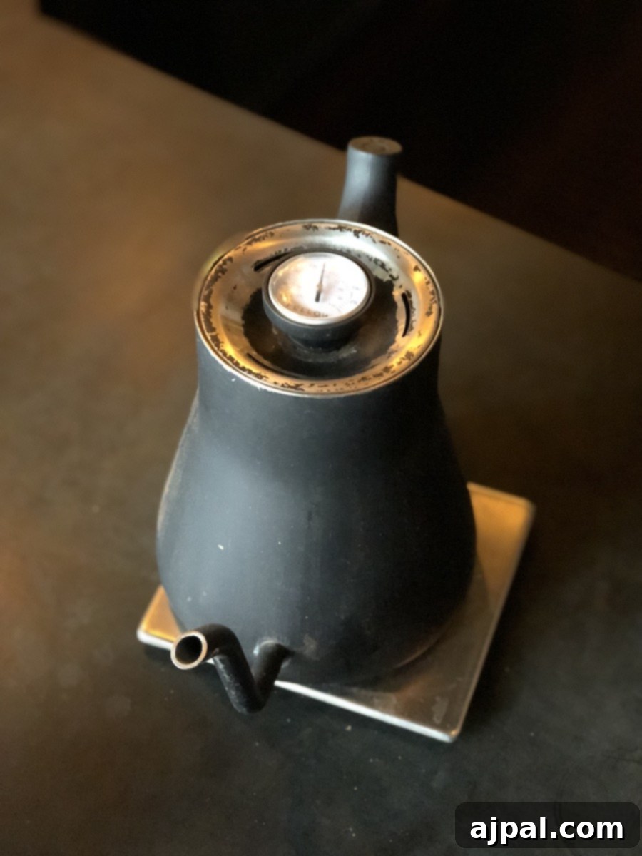 A black teapot sitting on top of a table in one of the best restaurants in Kansas City, providing unique Kansas City vacation ideas for food lovers.