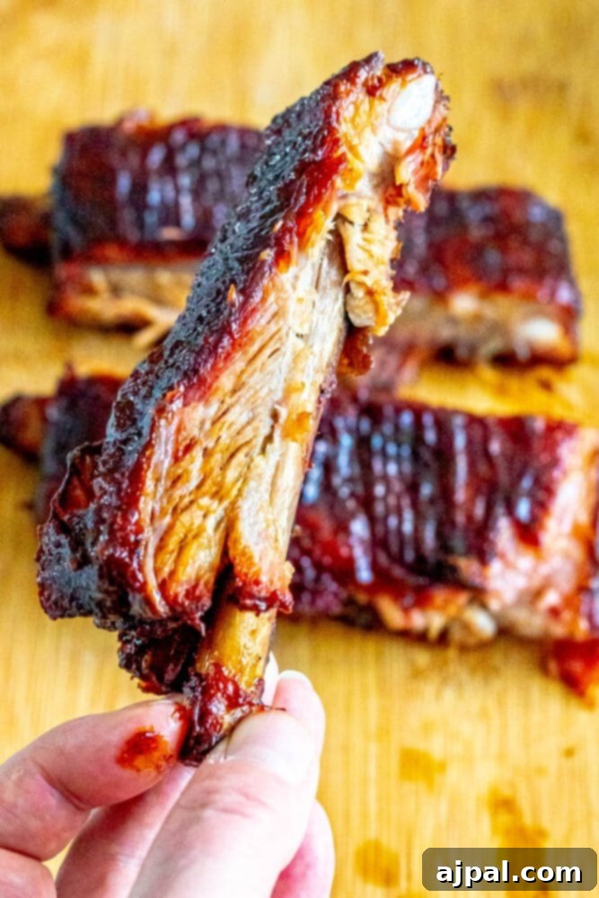 A person proudly holds a platter of beautifully smoked pork ribs on a wooden cutting board, ready to be enjoyed.