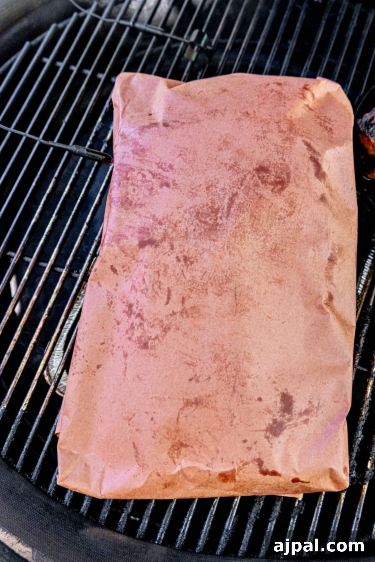 A foil-wrapped brisket returned to the smoker, continuing its slow cooking process.