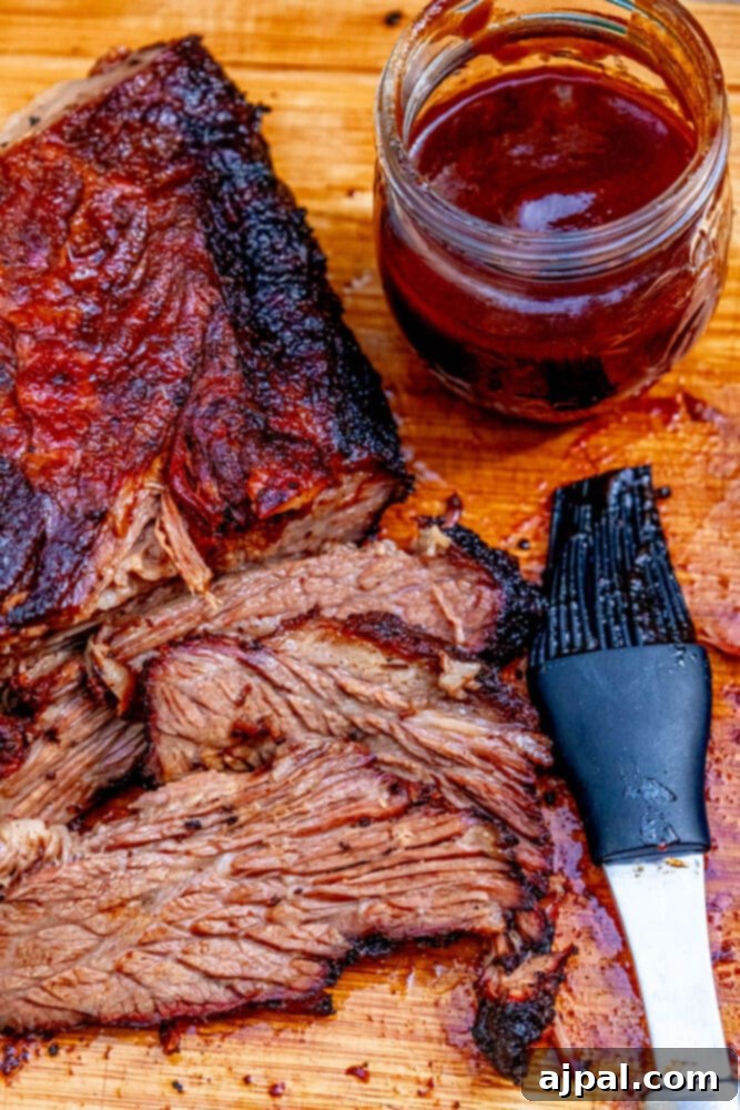 A large, beautifully smoked brisket, freshly removed from the grill, showcasing its dark, flavorful bark.