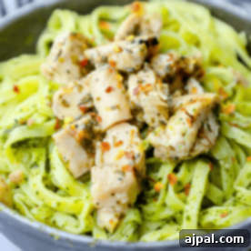A bowl of pasta with chicken and vibrant chimichurri pesto sauce, ready to eat.