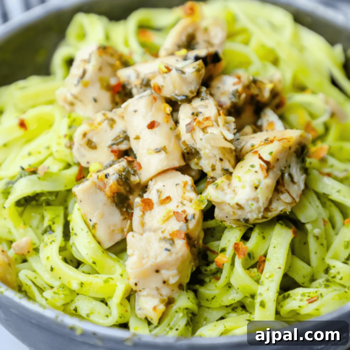 Close-up of a rustic bowl filled with chimichurri chicken pasta, garnished with fresh herbs and a drizzle of sauce.