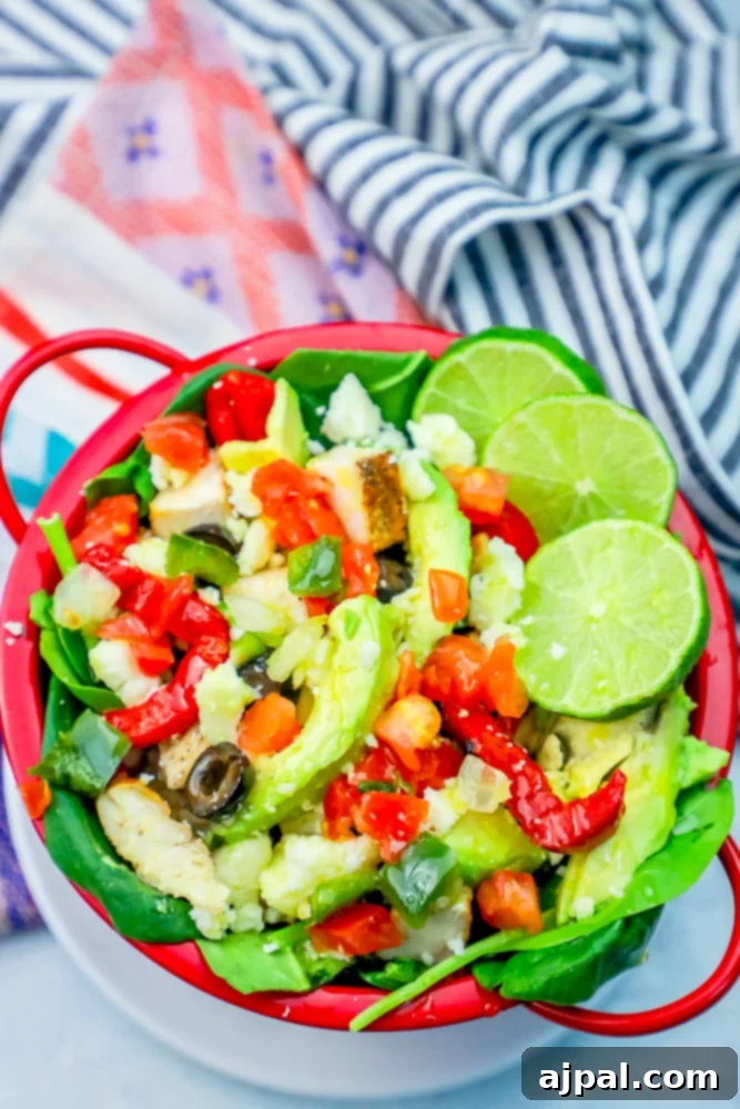 Quick and Delicious Chicken Taco Salad 2 A vibrant red and white bowl brimming with a delicious chicken taco salad, garnished with fresh lime wedges, creamy avocado slices, and dark olives.