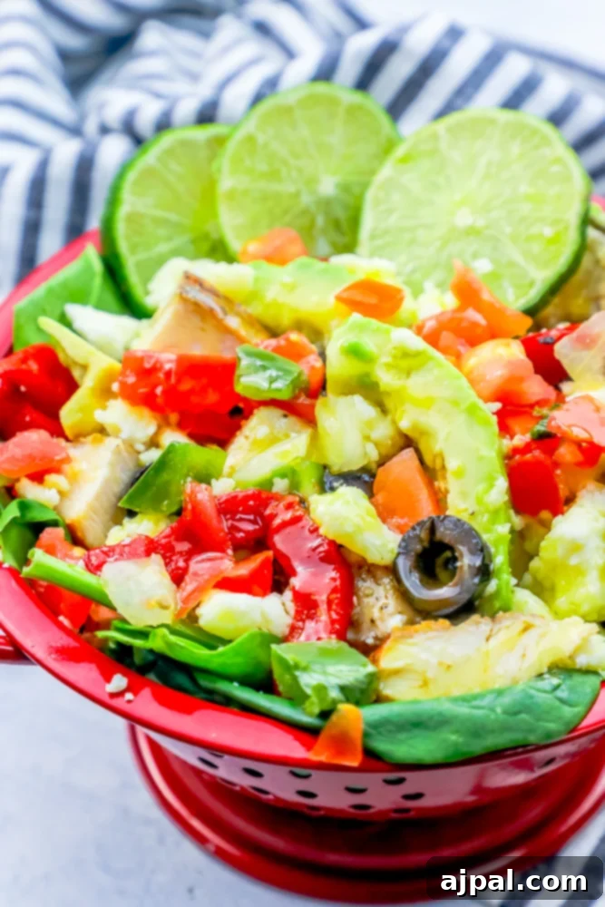 Quick and Delicious Chicken Taco Salad 7 A red bowl presents a low-carb keto chicken taco salad, beautifully garnished with fresh avocados, vibrant peppers, and black olives.