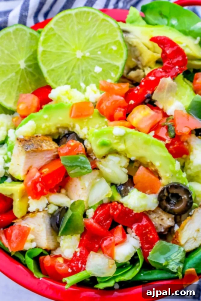 Quick and Delicious Chicken Taco Salad 4 A red bowl filled with a keto chicken taco salad, richly topped with avocado, ripe tomatoes, and fresh lime wedges for garnish.