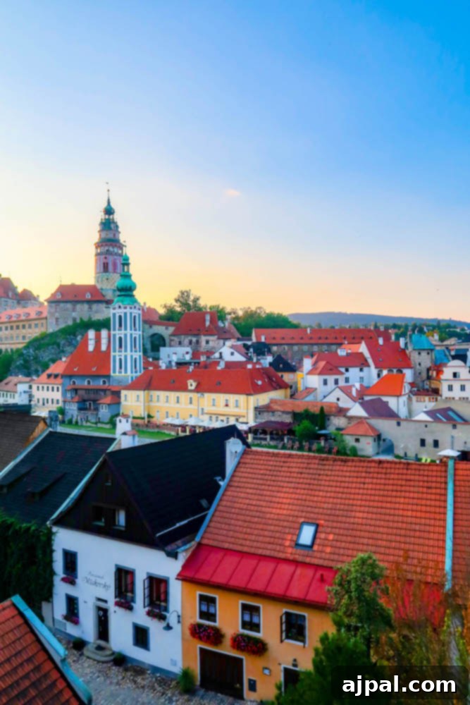 A stunning sunset over the old town of Cesky Krumlov, with its red roofs and historic buildings bathed in warm golden light, reflecting in the Vltava River.