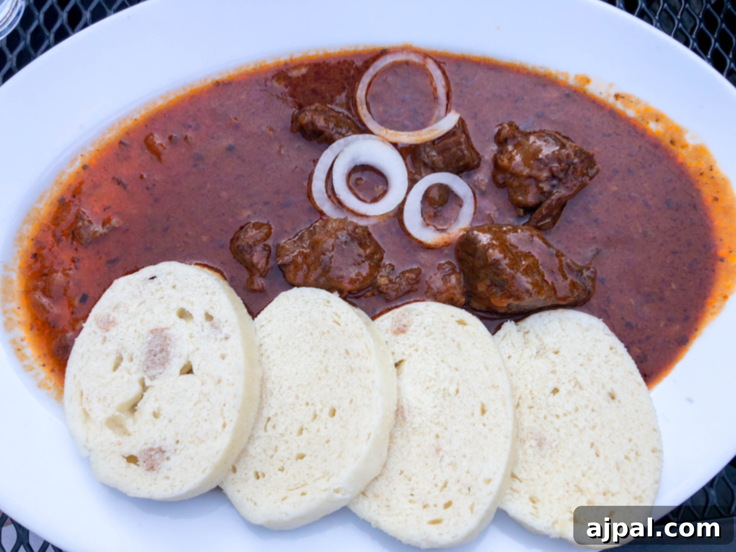 A hearty plate of Czech goulash served with traditional houskový knedlík (bread dumplings), a classic and comforting dish.
