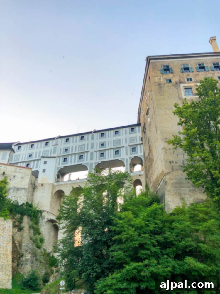 A grand view of Cesky Krumlov Castle's bridge connecting its parts, perched majestically above the Vltava River and the historic town.