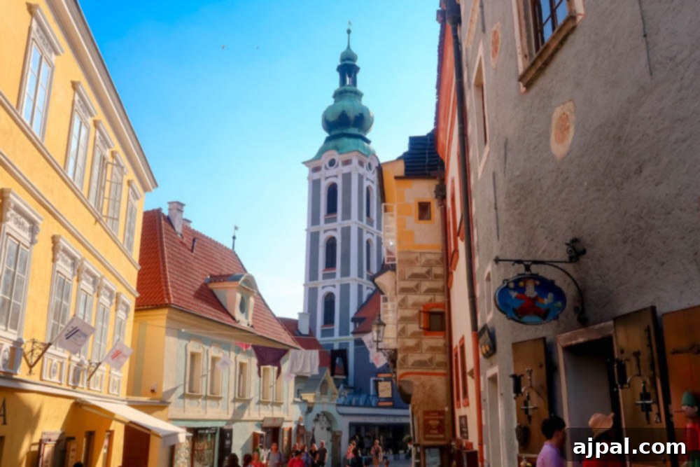 A picturesque narrow street in Cesky Krumlov, lined with colorful historic buildings, leading towards the distinct castle tower in the distance.