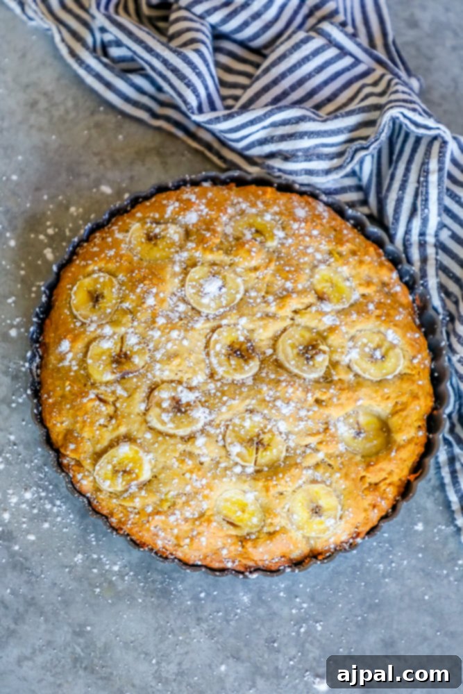 Effortless Apple Banana Loaf 3 A perfectly baked banana cake, generously dusted with powdered sugar, sitting on a white plate, ready to be enjoyed.