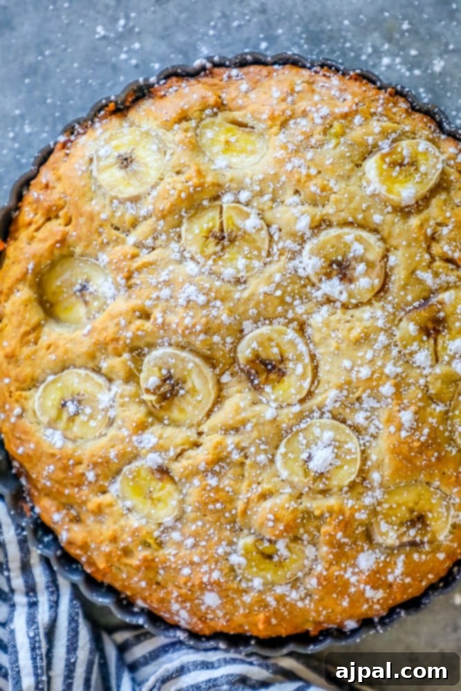 Effortless Apple Banana Loaf 5 A beautifully baked apple banana bread, topped with a delicate dusting of powdered sugar, presented enticingly on a cooling rack.