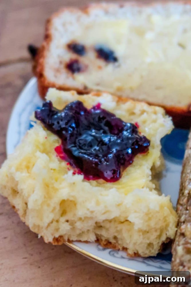 Freshly baked Irish Soda Bread, served with a dollop of vibrant red jam, on a simple plate.