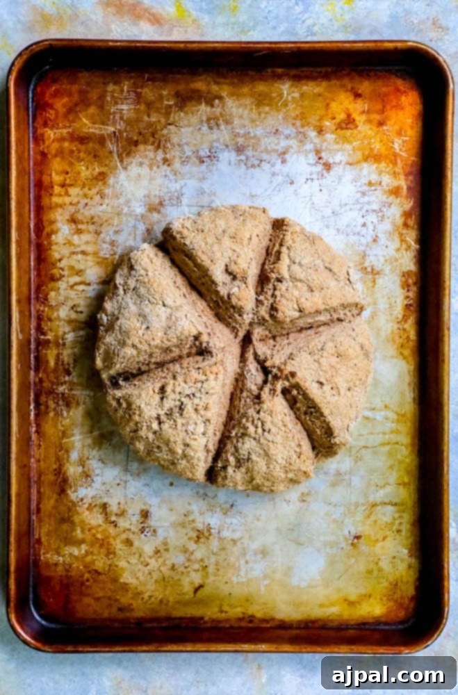 A golden-brown loaf of traditional Irish Brown Soda Bread on a baking sheet, scored with a distinct cross.