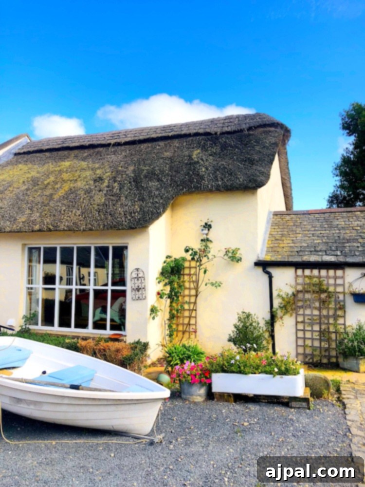 A charming traditional Irish thatched-roof cottage amidst lush greenery in the countryside.