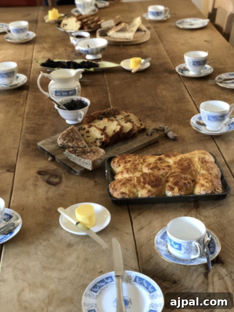 A delightful tea spread featuring various warm Irish breads, jams, and cups of tea, inviting guests to partake.