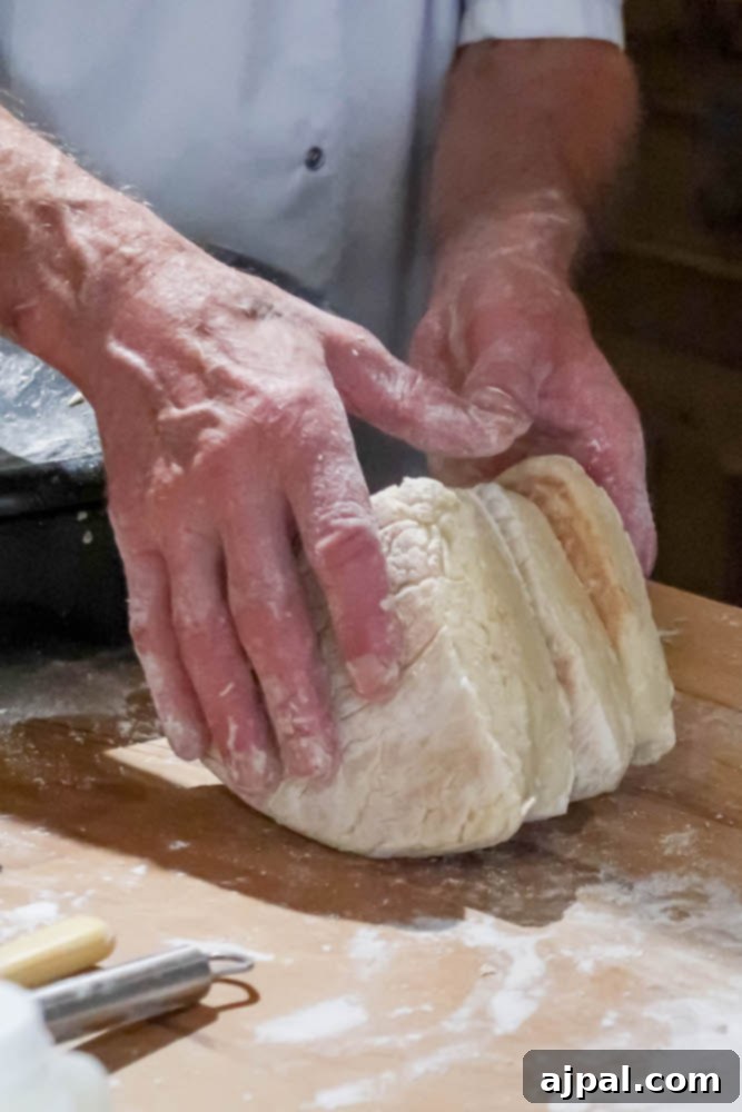 Expert hands kneading Irish Soda Bread dough on a rustic wooden table, demonstrating traditional bread-making techniques.