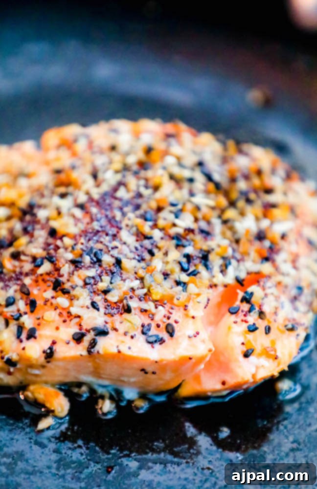 Perfectly baked salmon topped with generous everything bagel seasoning, glistening in a pan, ready to serve.