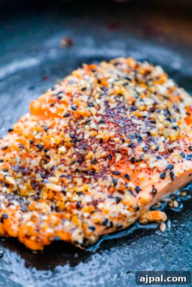 Baked everything bagel salmon sizzling in a hot pan, showcasing the golden-brown crust.